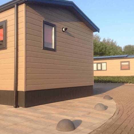 Antraciet betonnen parkeerbollen (Ø500 mm) zonder voet, geplaatst op een terras naast een chalet.