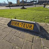 Grijze rubberen stootband met geel gepersonaliseerd parkeerbord "DIRK-TEUR" voor bedrijven.