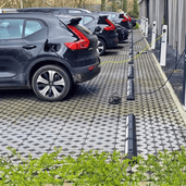Zwarte rubberen parkeerstop met witte 3M reflectoren, 180 cm, bij laadpalen voor elektrische auto's.