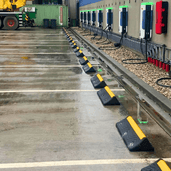 Zwarte rubberen wieldwinger met gele 3M reflectoren op een natte parkeerplaats.