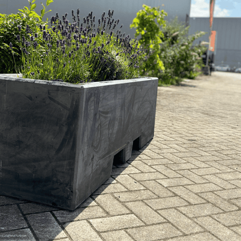 Antraciet betonnen plantenbak (165x50x50 cm) met lepelgaten, gevuld met lavendel, op een terras.