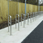 RVS fietsbeugels met tussenbuis en betonvoeten, Ø48 mm, in een rij op een betonnen ondergrond.