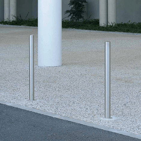 Twee RVS parkeerpalen Ø60 mm, zilverkleurig en strak vormgegeven, verankerd in een lichtgrijze ondergrond.