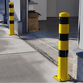 Gele en zwarte stalen rampaal Ø152 mm op voetplaat, staand op een betonnen ondergrond.