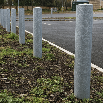 Zeven rampalen Ø152 mm van verzinkt staal, geplaatst langs een parkeerplaats