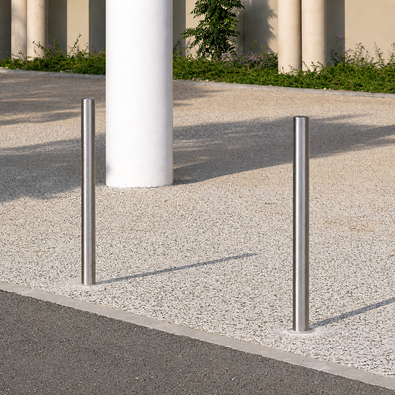 Twee RVS afzetpalen Ø60 mm, zilverkleurig en strak, verankerd in een moderne buitenomgeving.
