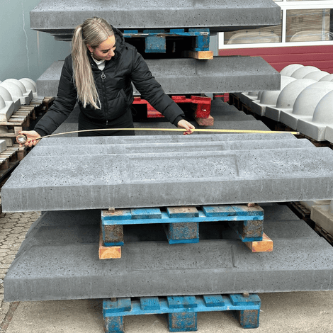 Grijze betonnen stootbanden met kentekenplaat uitsparing, gemeten door een vrouw.