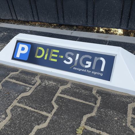 Witte stootband/parkeerbord met blauw, geel en wit "P DIE-SIGN designed for signing" logo.