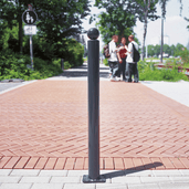 Antracietgrijze trottoirpaal Ø76 mm met bolle kop, gemonteerd op een tegelpad.