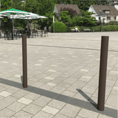 Trottoirpaal Ø76 mm met vlakke kop, bruin, op een betegeld plein.