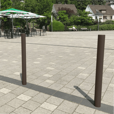 Trottoirpaal Ø76 mm met vlakke kop, bruin, op een betegeld plein.