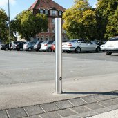 RVS uitneembare afzetpaal Ø89x900mm met slot, staand op een parkeerplaats.