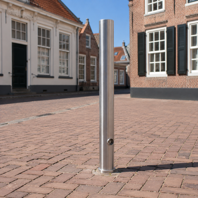 Uitneembare rvs afzetpaal 89 mm met driekantslot en betonvoet in een klassiek dorp straatje