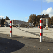 Twee wit-rode uitneembare afzetpalen Ø102 mm met betonvoet op een plein.