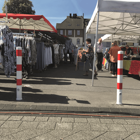 Wit-rode uitneembare afzetpaal Ø89 mm met betonvoet, staand op een marktplein.