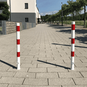 Twee wit-rode uitneembare parkeerpalen Ø60 mm met slotopties op een trottoir.