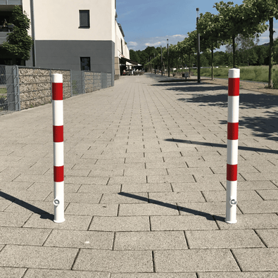 Twee wit-rode uitneembare parkeerpalen Ø60 mm met slotopties op een trottoir.