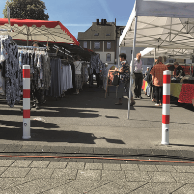 Witte en rood gestreepte uitneembare parkeerpalen Ø89 mm op een marktplein.