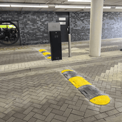 Gele en grijze verkeersdrempel van 5 cm hoog op een parkeerplaats, met gestructureerd oppervlak.