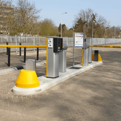 Grijs-geel verkeerseiland van 5 meter compleet met slagbomen, ticketzuilen en meldposten voor toegangscontrole.
