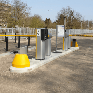 Grijs-geel verkeerseiland van 5 meter compleet met slagbomen, ticketzuilen en meldposten voor toegangscontrole.