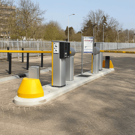 Grijs-geel verkeerseiland van 5 meter compleet met slagbomen, ticketzuilen en meldposten voor toegangscontrole.