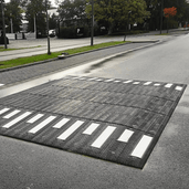 Zebra verkeersplateau, 400x350x10 cm, zwart met witte strepen, op een natte weg.
