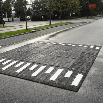 Zebra verkeersplateau, 400x350x10 cm, zwart met witte strepen, op een natte weg.